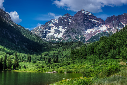 Majestic Maroon Bells peaks and Maroon Lake on a sunny day and blue sky in summer near Aspen, Colorado