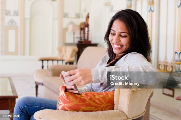 Young Indian Woman Reading Funny Messages On Mobile Phone Stock Photo - Download Image Now