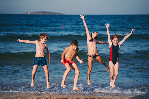 Happy kids on beach holiday jumping in the water
