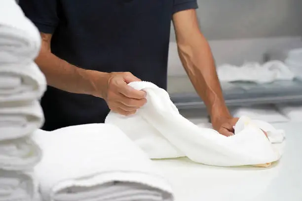 Photo of Laundry hotel. A man lays out a white towel.