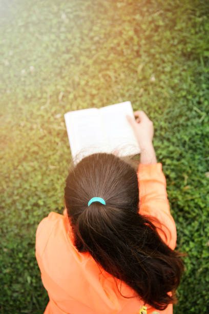 istock Smiling woman relaxing in grass and reading a book 1087925704