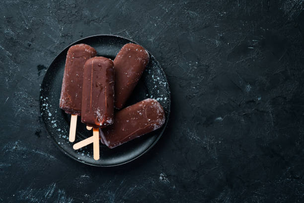 istock Chocolate ice cream on a stick. On a black background. Top view. Free copy space. 1087927524