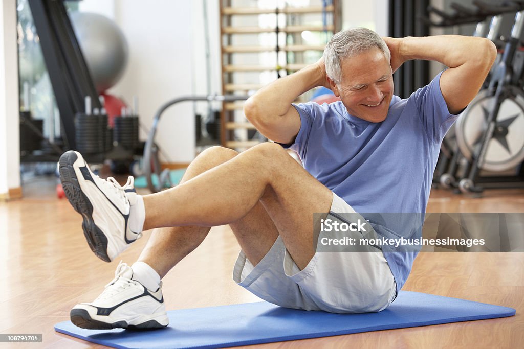 Senior hombre haciendo Sit Ups en el gimnasio - Foto de stock de Gimnasio libre de derechos