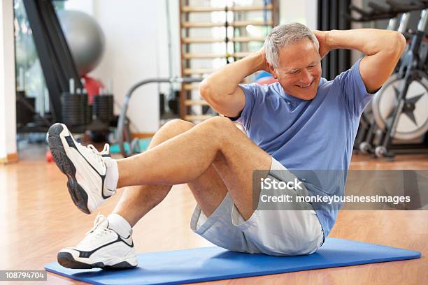 Senior Hombre Haciendo Sit Ups En El Gimnasio Foto de stock y más banco de imágenes de Gimnasio - Gimnasio, Ejercicio físico, Estilo de vida saludable