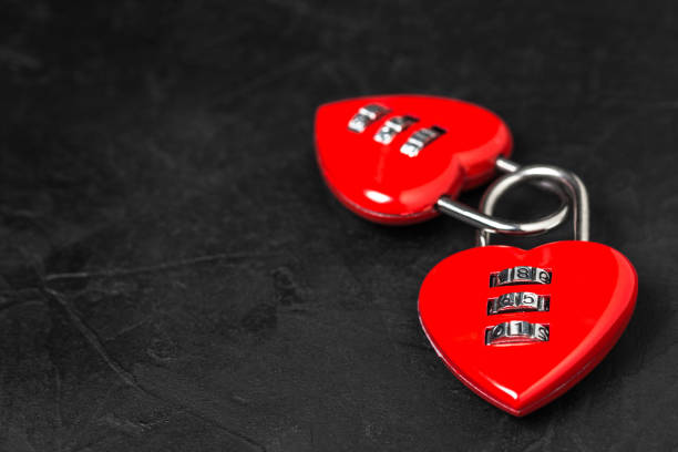 istock Valentine's Day background. Two red heart shape locks with copy space on black texture background 1087976760