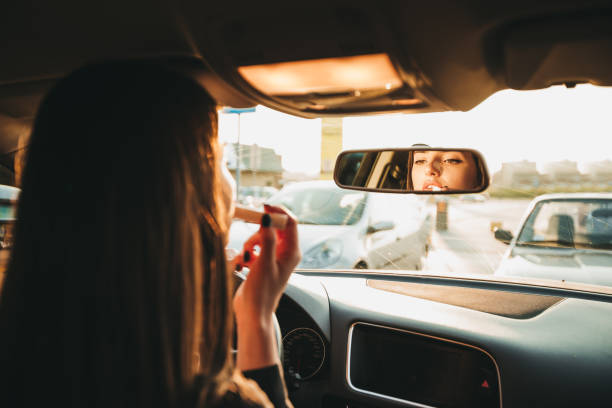 Businesswoman fixing make-up in rear view mirror