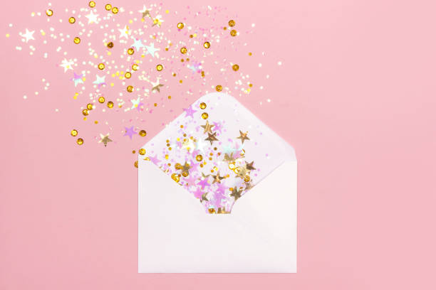 istock Golden and pink confetti scattered from envelope on pastel pink background. 1087996312