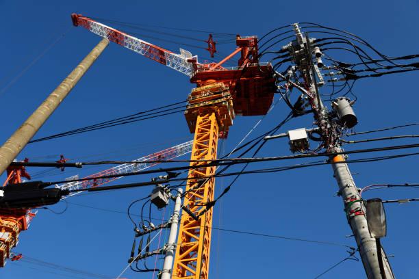 Low angle view of tall crane with electrical line against clear sky.