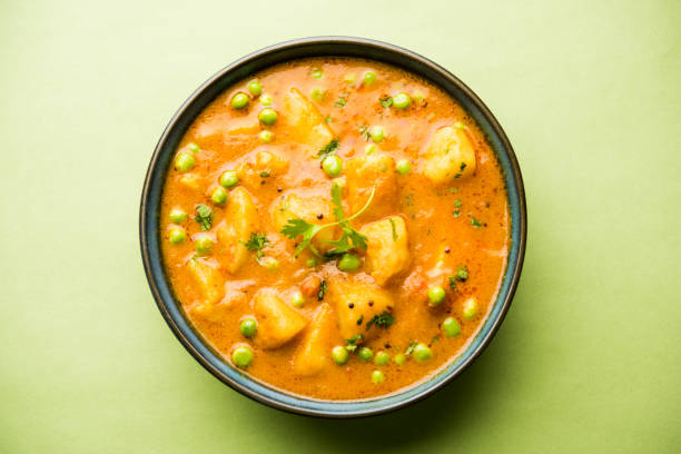 Indian Aloo Mutter curry - Potato and Peas immersed in an Onion Tomato Gravy and garnished with coriander leaves. Served in a Karahi/kadhai or pan or bowl. selective focus stock photo
