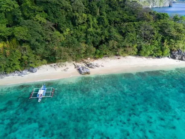 The photo shows a fine white sand beach and crystal clear water of an island in the Bacuit Bay in Palawan, Philippines. Shot with the DJI Mavid Pro