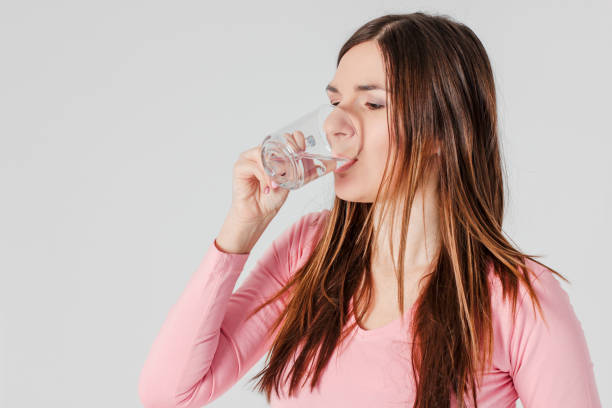 istock Young brunette woman drinking pure water isolated on grey backgr 1088039088