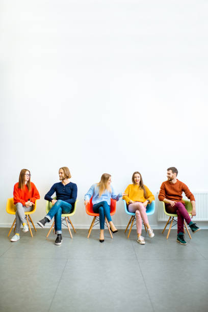 istock Young people sitting in a row on the white wall background 1088059062