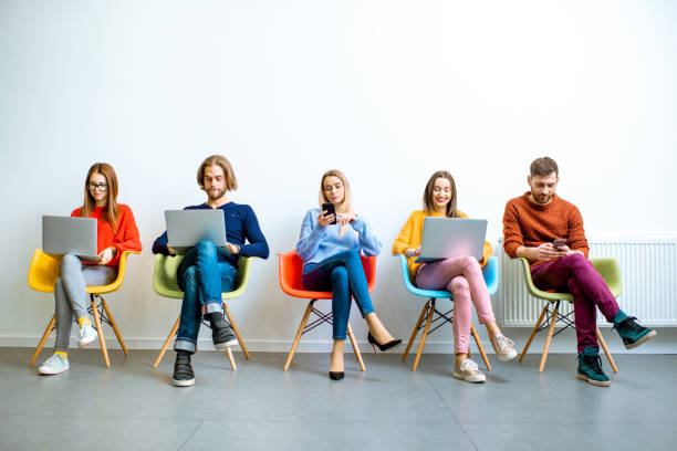 istock Young coworkers sitting with gadgets on the white wall background 1088059074