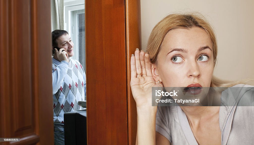 A husband unaware that his wife is listening nearby  Jealous wife, overhearing a phone conversation her husband Couple - Relationship Stock Photo