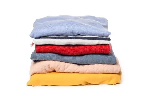Photo of Stacks of folded clothes on white background