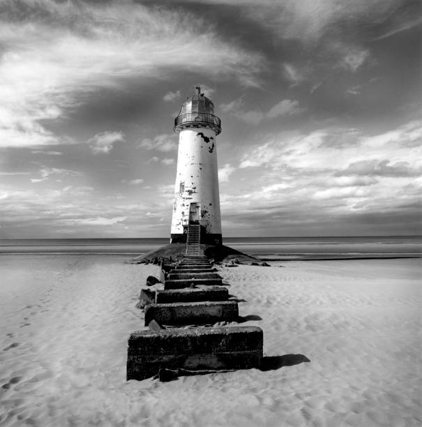 istock black and white photograph of a lighthouse on a sandy beach with a stone pathway infront 1088074588