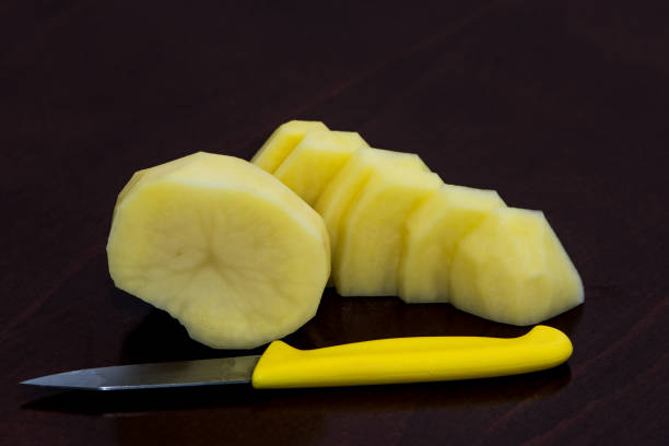 Peeled potato cutted on the small slices on the wooden board ready for cooking