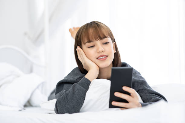 istock Beautiful Attractive Asian woman lying on white bed using smartphone using social media in bedroom smile and happiness with social media and shopping online,Lifestyle in Holidays Concept 1088078216
