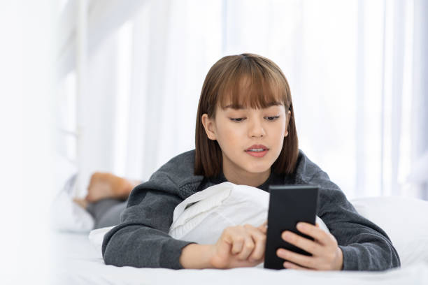 istock Beautiful Attractive Asian woman lying on white bed using smartphone using social media in bedroom smile and happiness with social media and shopping online,Lifestyle in Holidays Concept 1088078230