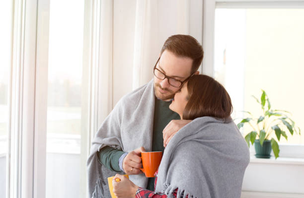 istock Couple covered with blanket and with hot tea beside window 1088082458