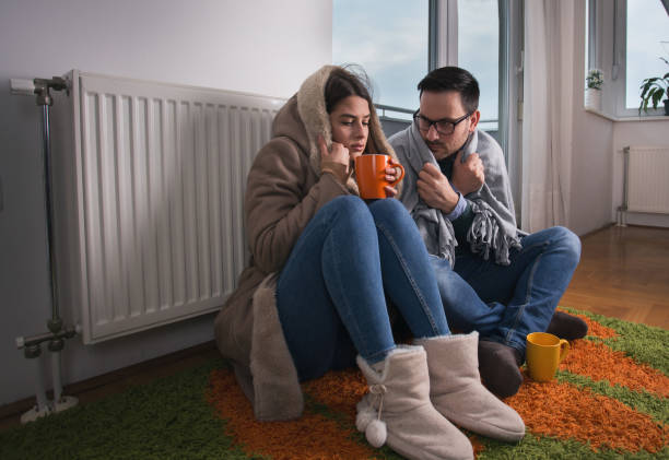 couple sitting beside radiator - tremendo imagens e fotografias de stock