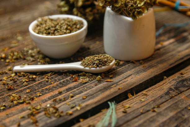istock Dried basil spice in a small ceramic bowl, small white ceramic spoon and twig of dried basil 1088083772