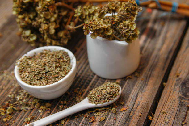 istock Dried basil spice in a small ceramic bowl, small white ceramic spoon and twig of dried basil 1088083794