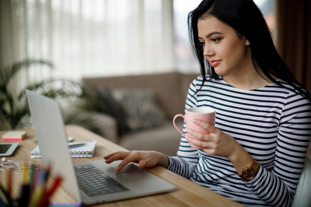 istock Young woman working on laptop and drinking coffee 1088105354