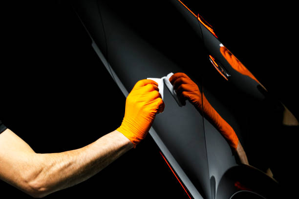 Car polish wax worker hands polishing car. Buffing and polishing vehicle with ceramic. Car detailing. Man holds a polisher in the hand and polishes the car with nano ceramic. Tools for polishing stock photo
