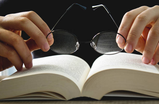 istock Male hand holding eyeglasses on open book. 1088158266