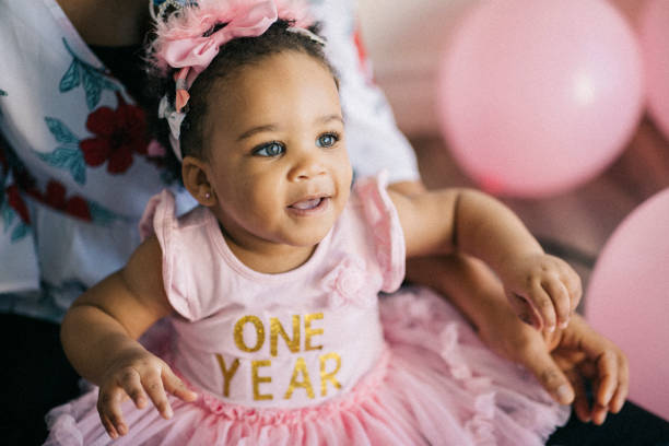 hermosa niña un año de edad, vestido de color rosa, celebrando su primer cumpleaños. - globo decoración fotos fotografías e imágenes de stock