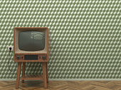 Old retro TV in the interior of the living room stands on the parquet floor on a background of a wall with green abstract wallpaper. Copy space.