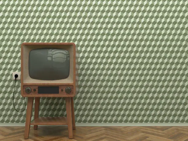 Photo of Old retro TV in the interior of the living room stands on the parquet floor on a background of a wall with green abstract wallpaper. Copy space.