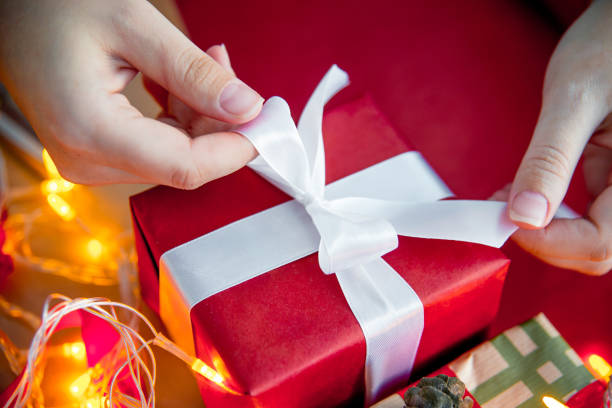 istock Female hands wrapping red christmas gift boxes 1088165632