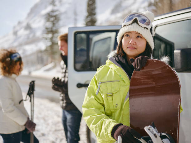Young Adults Enjoying a Winter Outing Young adults enjoying a winter outing, driving their vehicles in the mountains. japanese snowboarder stock pictures, royalty-free photos & images