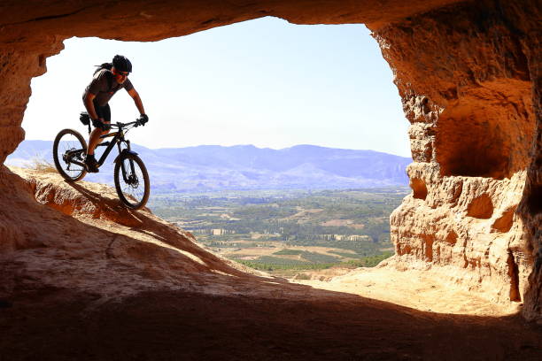 fahrer mann absteigend sehr schnell zu einer höhle mit einem mountainbike - mountain pass stock-fotos und bilder