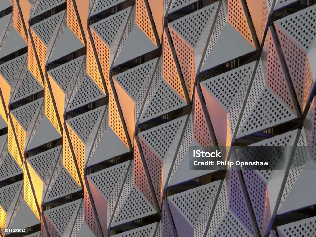 modern steel cladding with angular geometric patterns  and square holes in a shiny metallic finish with colored reflection on the wall of a car park in leeds modern steel cladding with angular geometric patterns  and square holes in a shiny metallic finish with colored reflection on the wall of a car park in leeds university district Architecture Stock Photo