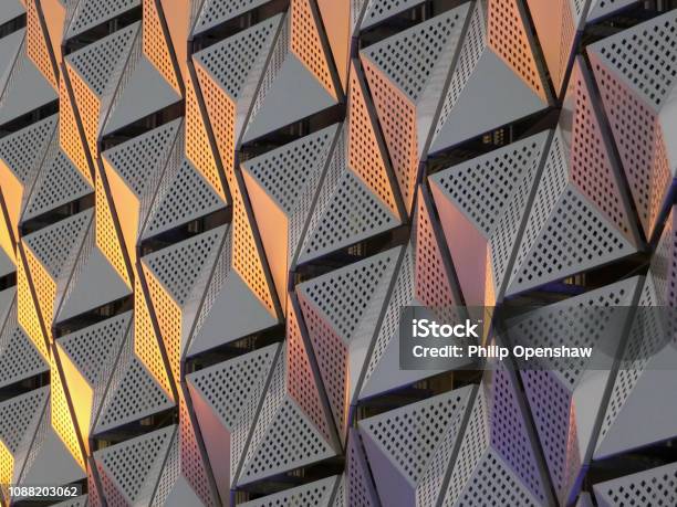 Modern Steel Cladding With Angular Geometric Patterns And Square Holes In A Shiny Metallic Finish With Colored Reflection On The Wall Of A Car Park In Leeds Stock Photo - Download Image Now