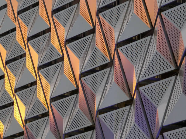 modern steel cladding with angular geometric patterns  and square holes in a shiny metallic finish with colored reflection on the wall of a car park in leeds - architecture feature imagens e fotografias de stock