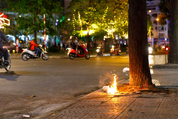 Piece of garbage burns next to a tree on a street in Saigon, Vietnam stock photo