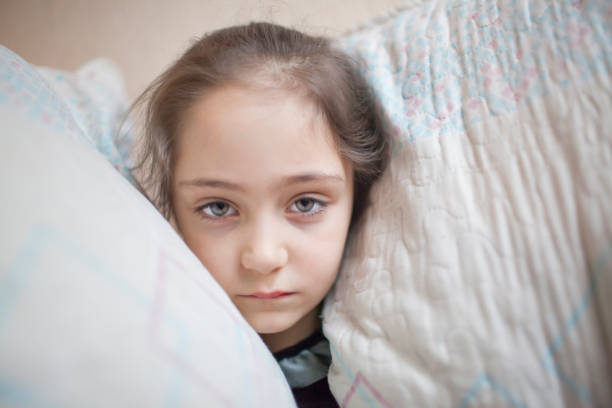 istock Little girl squeezes her head with pillows 1088205812