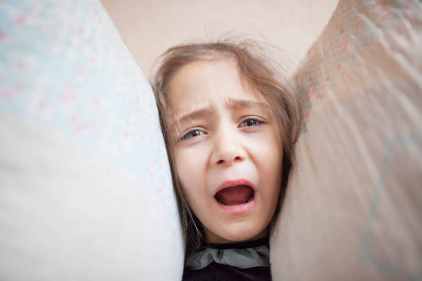 istock Little girl squeezes her head with pillows 1088205940