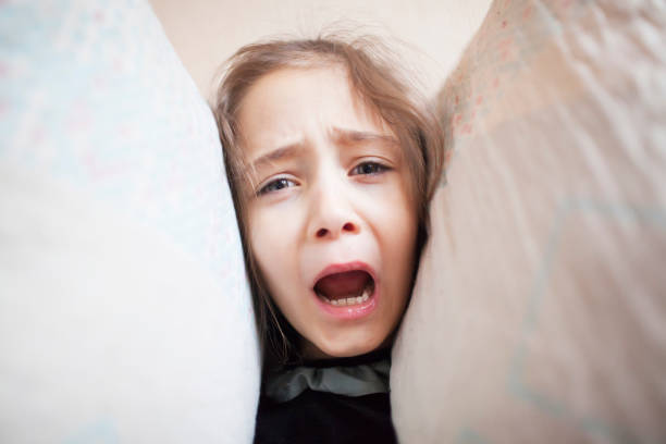 istock Little girl squeezes her head with pillows 1088205952