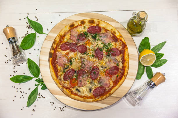 istock appetizing pizza with sausages, bacon, basil, spices and olive oil on a white table, flat lay 1088221442