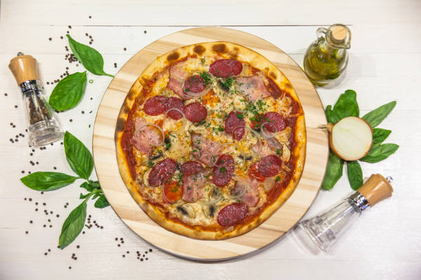 istock appetizing pizza with sausages, bacon, basil, spices and olive oil on a white table, flat lay 1088221468