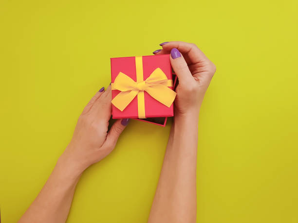 istock women's hands hold a gift box on colored paper 1088230424