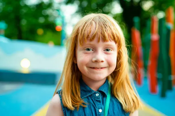 Happy Red haired young girl on a playground in Copenhagen Denmark on a sunny day during summer.