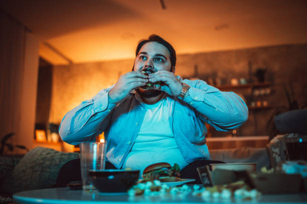 istock Fat man eating fast food and watching TV 1088234730