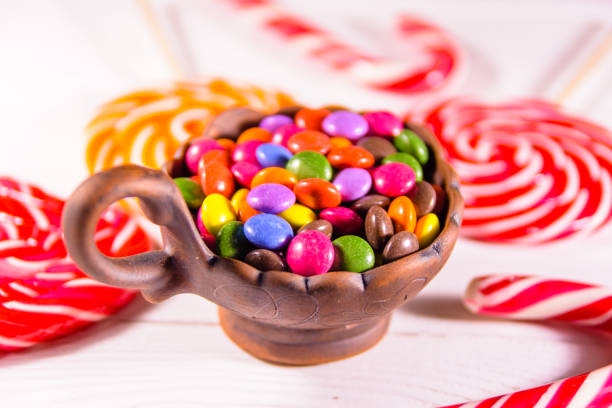 istock Ceramic bowl with colored candies and lollipops on a wooden table 1088237650