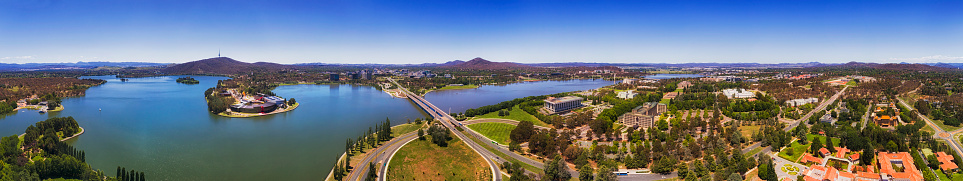 Ultra wide aerial panorama over Canberra capital city of Australia from parliament house on the hill to distant TV tover behind BUrley Griffin lake.